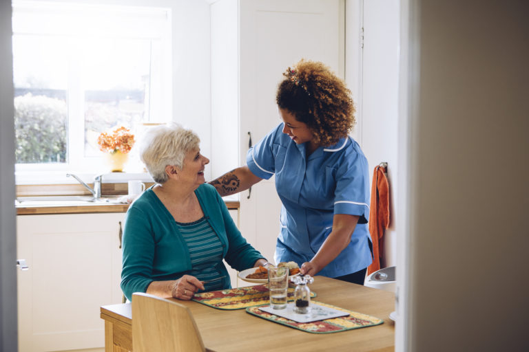 auxiliar de saúde e geriatria a prestar assistência a uma pessoa idosa