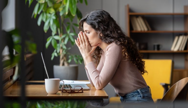 uma mulher a trabalhar no computador, com as mãos em frente à cara, demonstrando sinais de frustração, que materializa que está a pensar estou desmotivado no trabalho