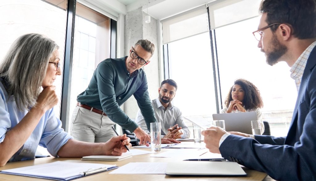 Reunião num escritório em ambiente corporativo, demonstrando que uma das pessoas conseguiu desenvolver as suas capacidades de como ser assertivo